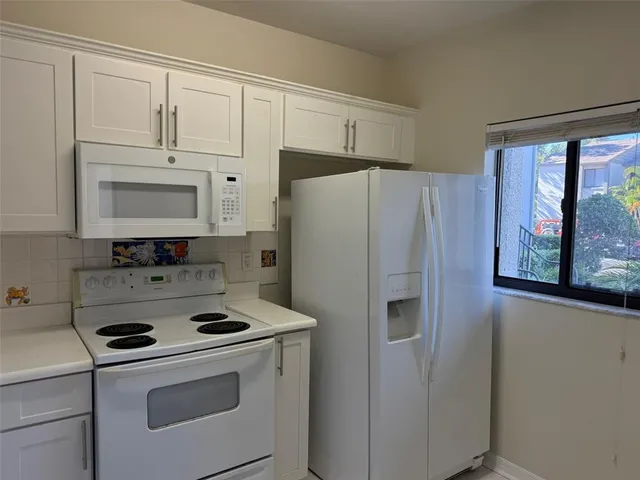 a white refrigerator freezer and a stove sitting inside of a kitchen