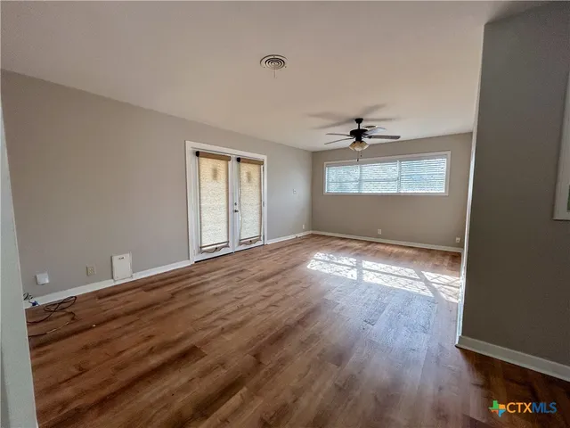 an empty room with wooden floor and windows
