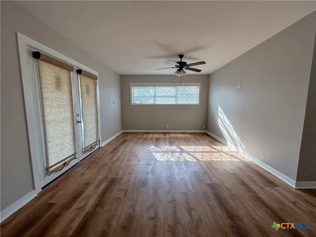 an empty room with wooden floor and windows