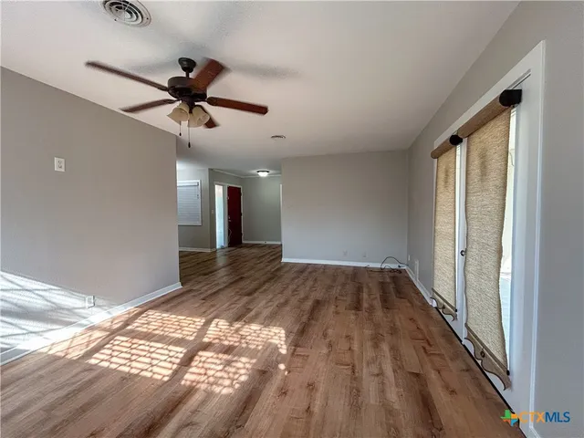 a view of empty room with wooden floor and fan