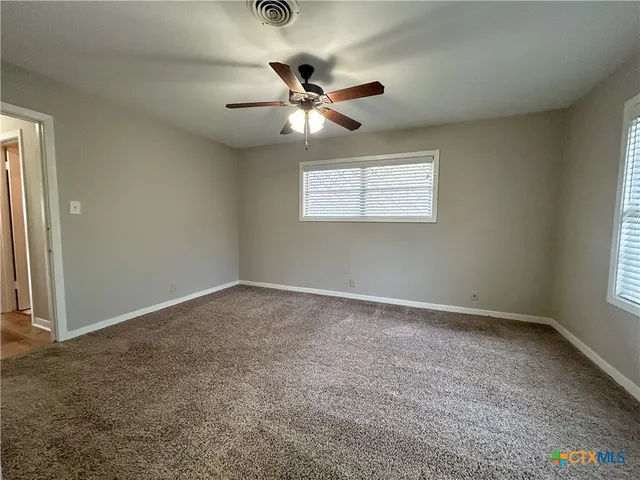an empty room with a window and a fan