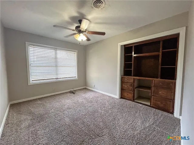 a view of an empty room with a window and cabinet