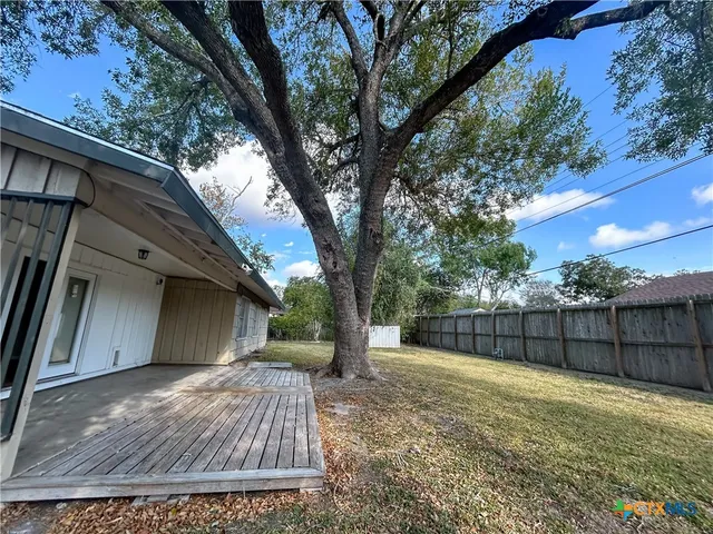 a view of backyard with wooden fence and large trees