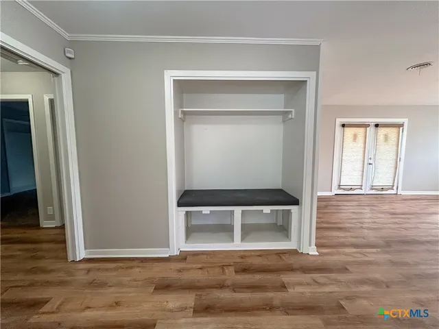 a view of empty room with wooden floor and fan