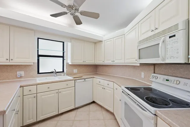 a kitchen with cabinets appliances a sink and a window