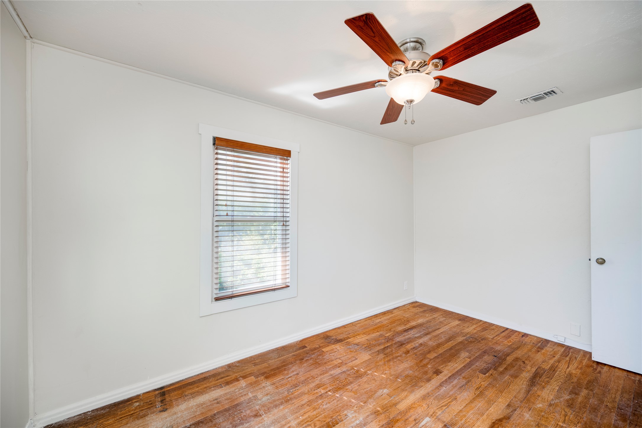 4804 Tanney Street Austin, TX 78721 - Photo 26 of 40 A well-lit bedroom with rich wood flooring and a refreshing ceiling fan.