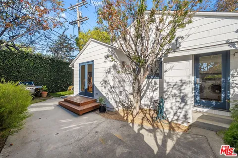 a view of a patio with table and chairs potted plants and large tree