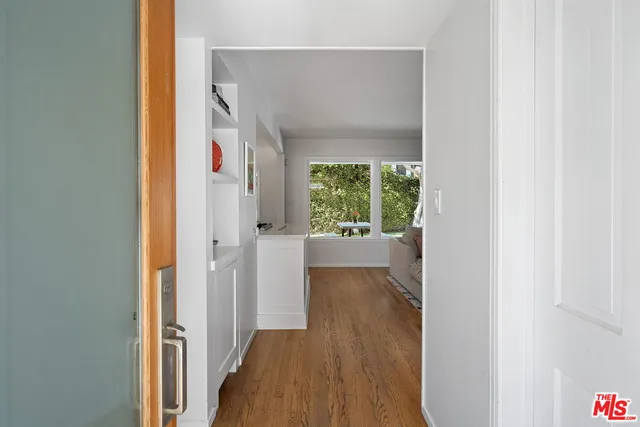 a view of a hallway with wooden floor and a bathroom