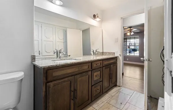 a bathroom with a granite countertop sink a toilet and a mirror