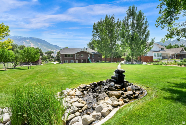 13658 South Fort Street Draper, UT 84020 - Photo 70 of 87 Expansive green lawn with a rock water feature, mature trees, and mountain scenery