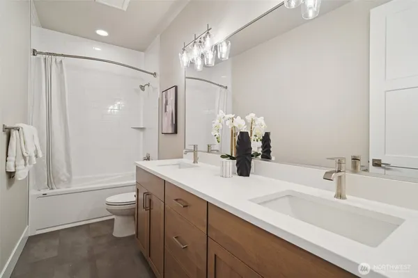a bathroom with a sink a toilet a large mirror and shower