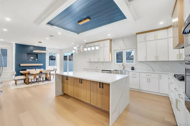 a large white kitchen with stainless steel appliances granite countertop a stove and a sink