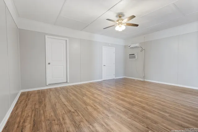 a view of an empty room with chandelier fan and wooden floor