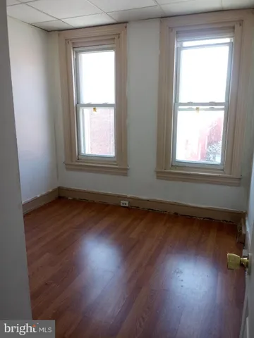 an empty room with wooden floor cabinet and windows
