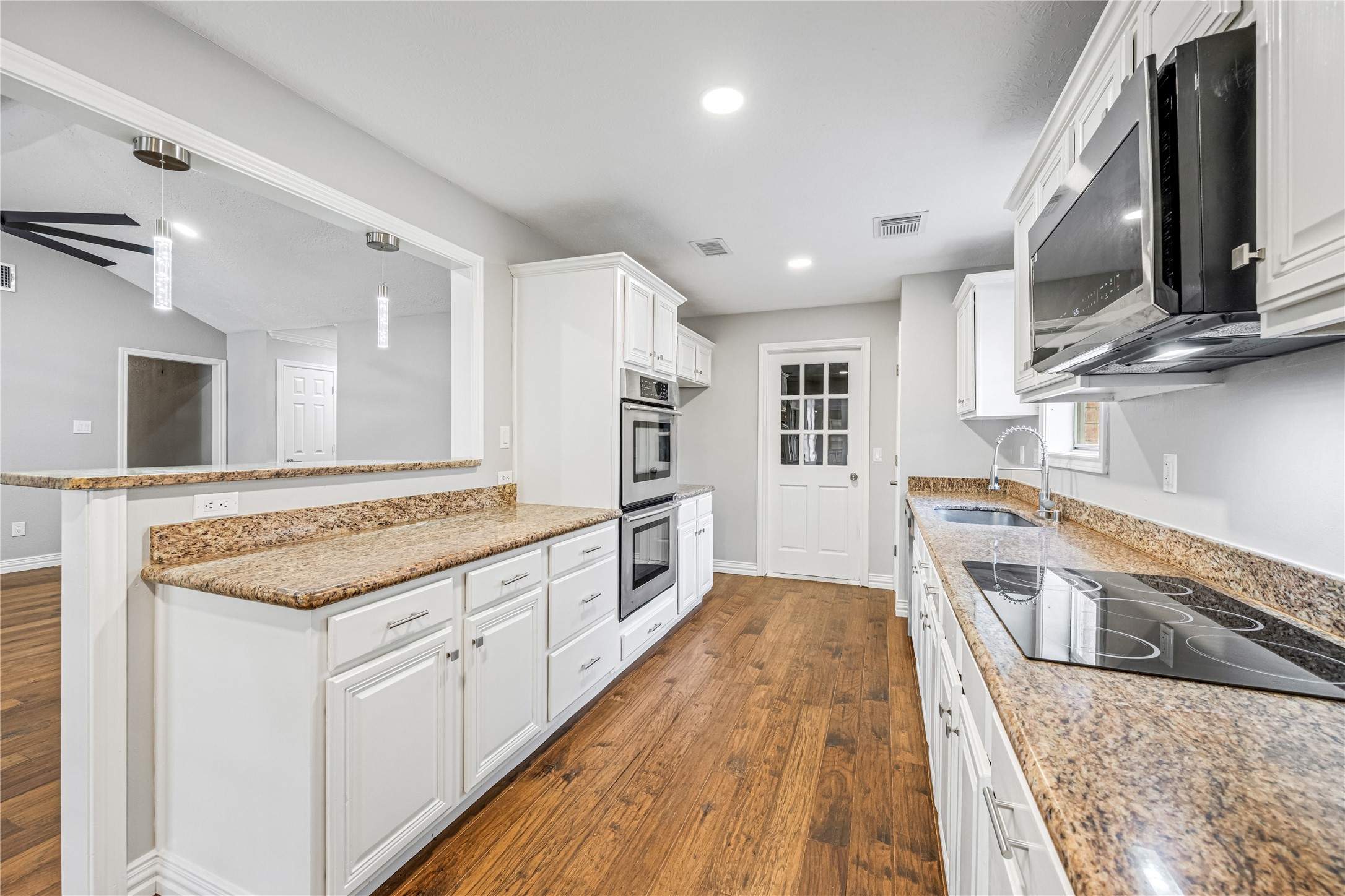 9806 Tanager Lane Conroe, TX 77385 - Photo 11 of 28 a large kitchen with stainless steel appliances granite countertop a lot of counter space and wooden floor