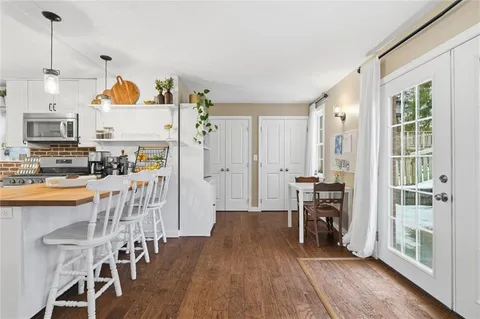 a living room with stainless steel appliances kitchen island granite countertop furniture and a wooden floor