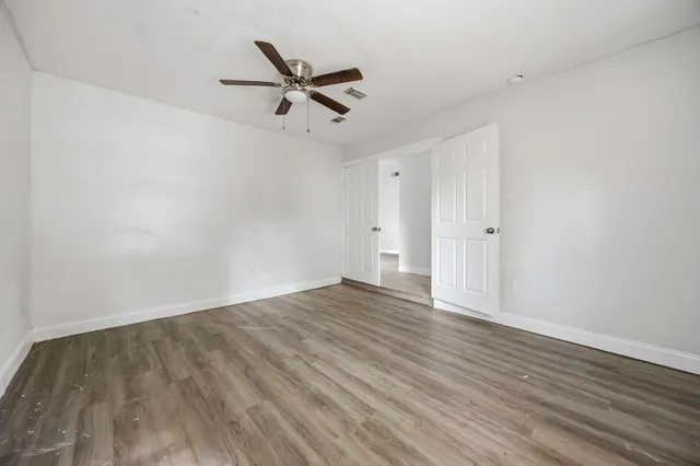 a view of empty room with wooden floor and ceiling fan
