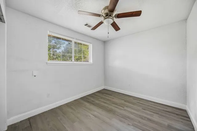 an empty room with a window and a ceiling fan