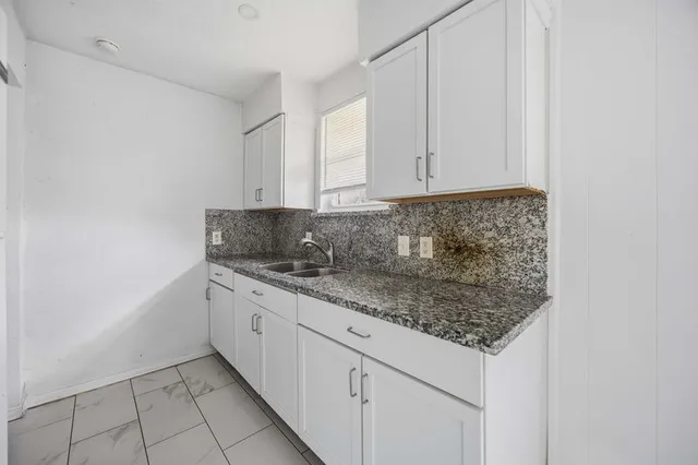 a kitchen with stainless steel appliances granite countertop a sink and dishwasher with white cabinets