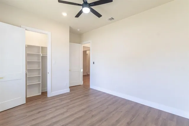 an empty room with wooden floor and ceiling fan