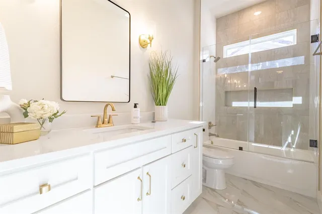a bathroom with a granite countertop sink mirror and a bathtub