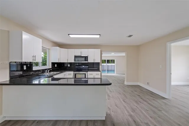 a kitchen with granite countertop a stove top oven and cabinets