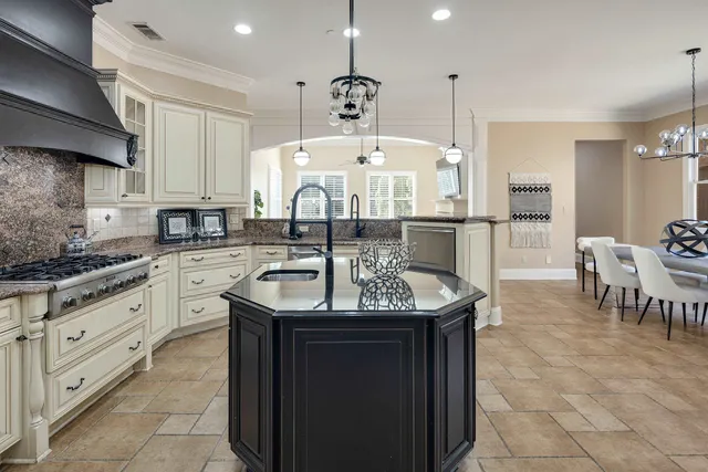 a kitchen with kitchen island granite countertop a sink a center island a stove and a window