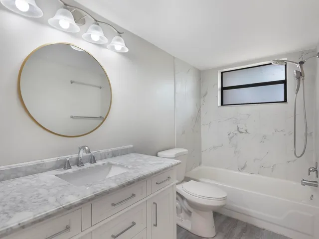 a bathroom with a granite countertop toilet a sink and a mirror