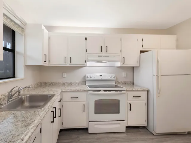 a kitchen with cabinets appliances a sink and a counter top space