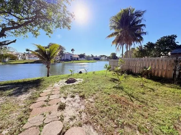 a view of a lake with a yard and palm trees