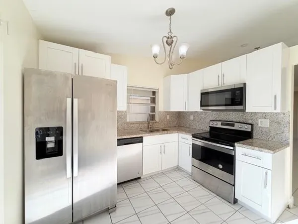 a kitchen with a refrigerator a microwave and white cabinets