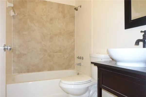 a bathroom with a granite countertop sink a toilet a mirror and bathtub