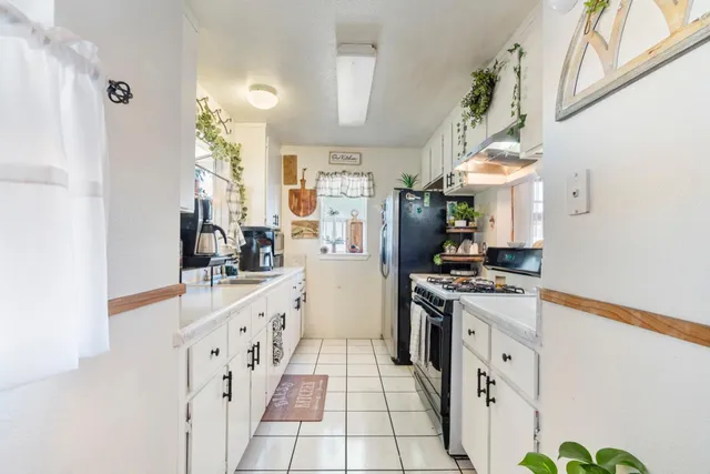 a kitchen with stainless steel appliances a white stove top oven a sink a chimney and a refrigerator