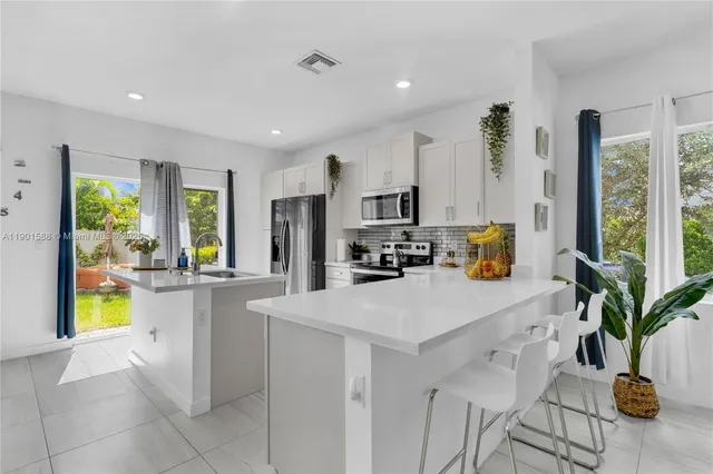 a kitchen with stainless steel appliances a sink a counter top space cabinets and a potted plant