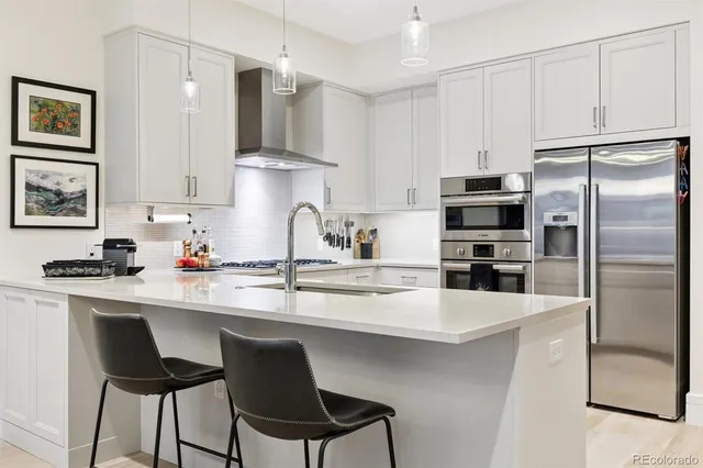 a kitchen with stainless steel appliances a refrigerator a stove a sink and white cabinets