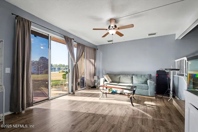 a living room with furniture a flat screen tv and a floor to ceiling window