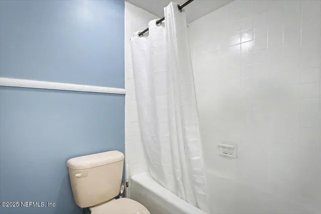 a white toilet sitting next to a shower