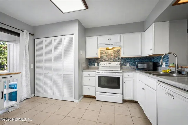 a kitchen with white cabinets and white appliances