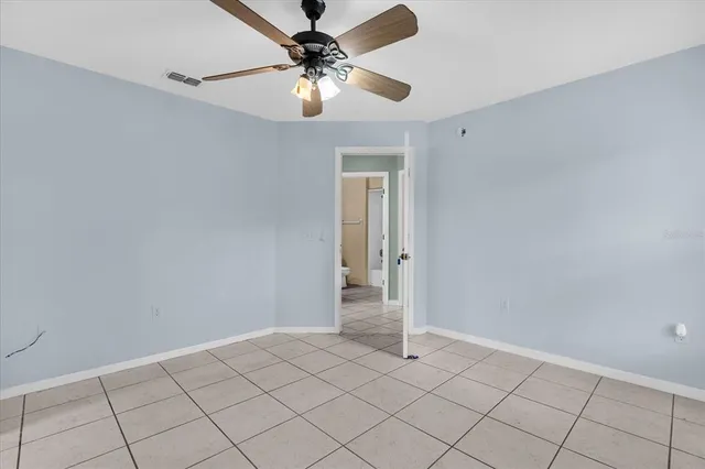 a view of an empty room and chandelier fan