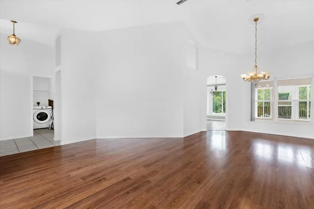 a view of an empty room with wooden floor and windows