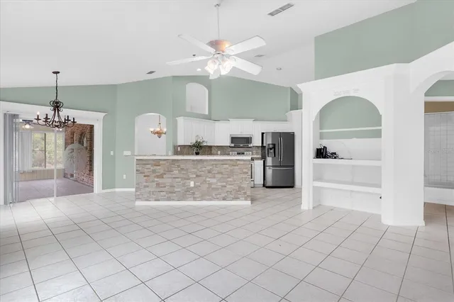 a large white kitchen with a sink and chandelier