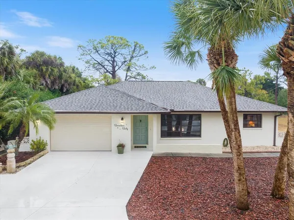 front view of a house with a yard and palm trees