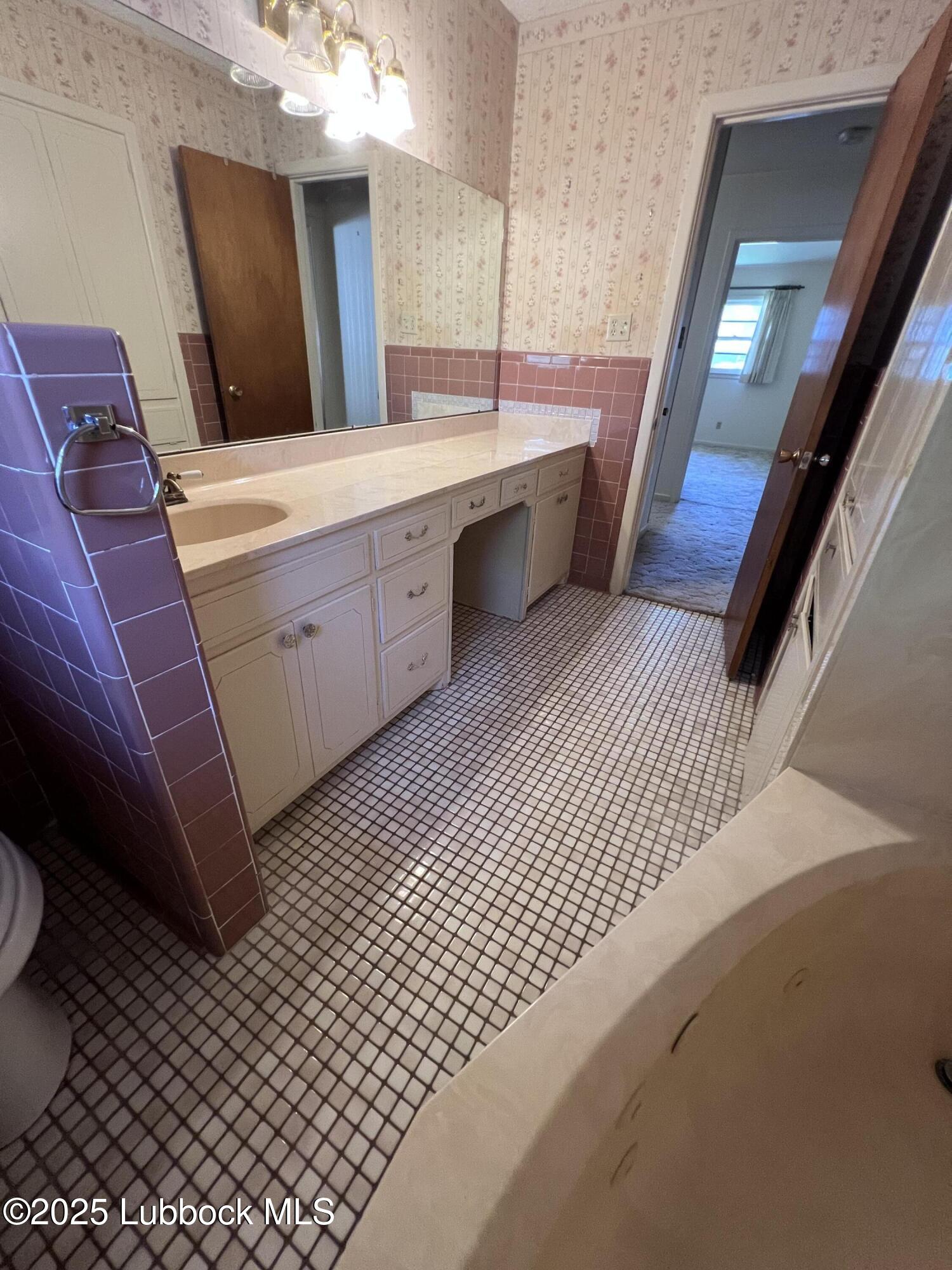 2304 54th Street Lubbock, TX 79412 - Photo 12 of 18 a bathroom with a sink a mirror and a toilet
