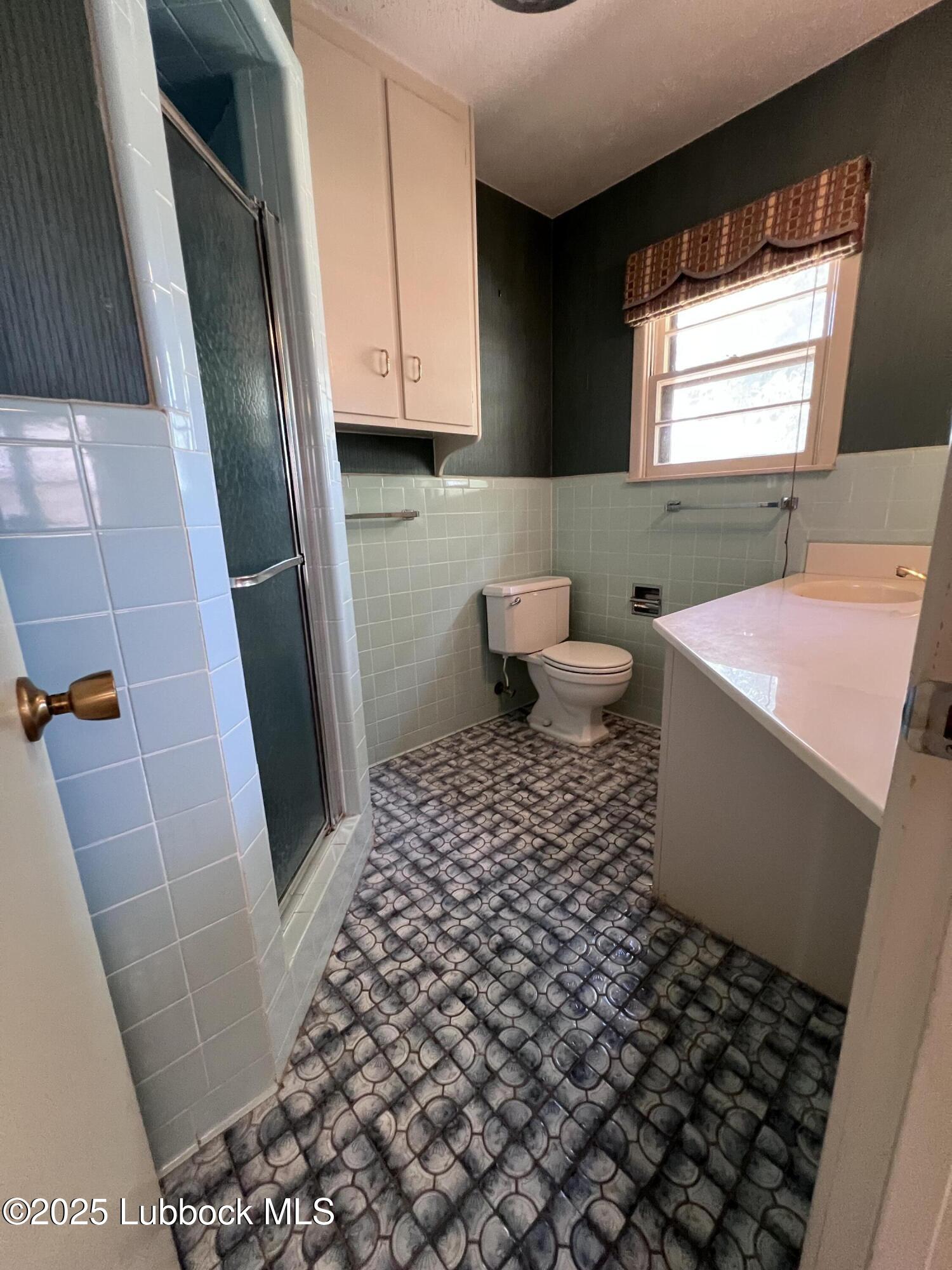 2304 54th Street Lubbock, TX 79412 - Photo 10 of 18 a bathroom with a sink a toilet a window and vanity
