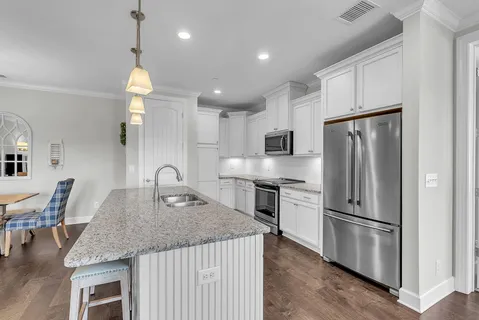 a kitchen with granite countertop stainless steel appliances a refrigerator a stove a sink a dining table and chairs