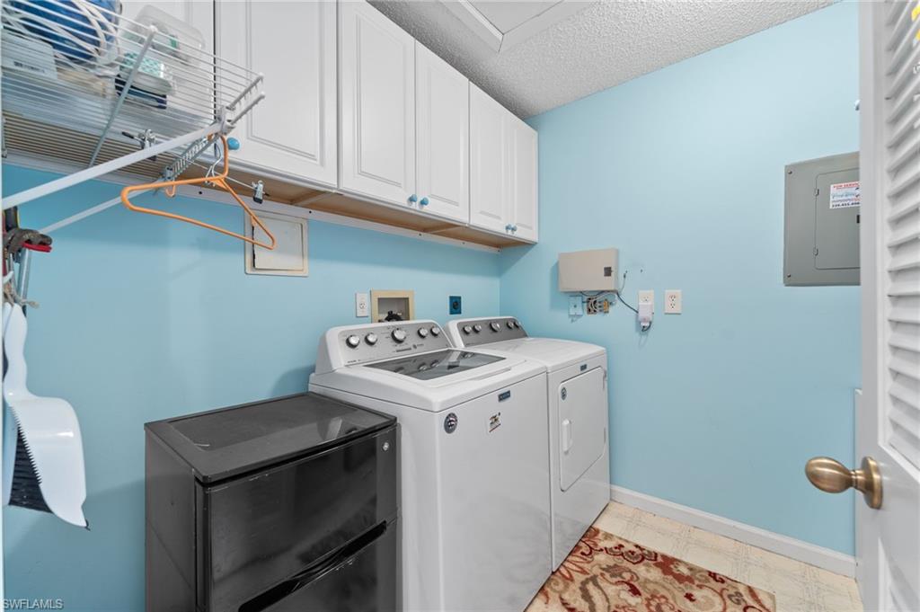 5928 Cranbrook Way, Unit D202 Naples, FL 34112 - Photo 12 of 23 Washroom featuring electric panel, a textured ceiling, washing machine and dryer, baseboards, and cabinet space