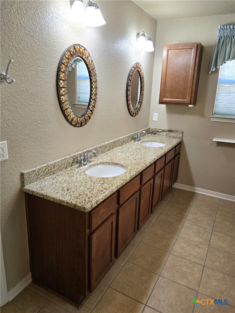 6308 Roxbury Avenue Temple, TX 76502 - Photo 17 of 26 a bathroom with a granite countertop sink and a mirror