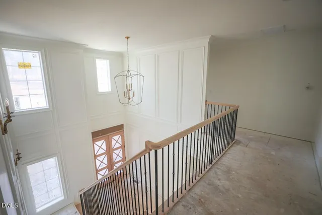an empty room with a chandelier fan and windows