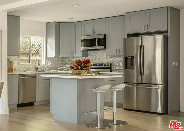 a kitchen with granite countertop a sink stainless steel appliances and window