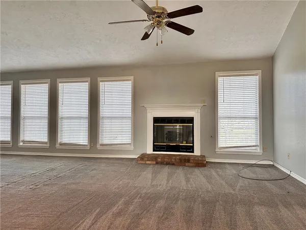 an empty room with windows and fireplace